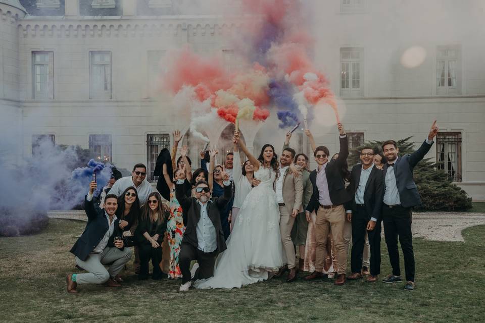 novios con invitados levantando bengalas de humo de colores en el casamiento