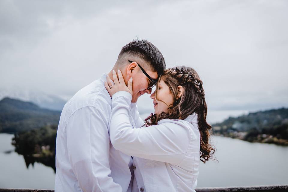 Novia tocándole la cara a su novio frente a un lago