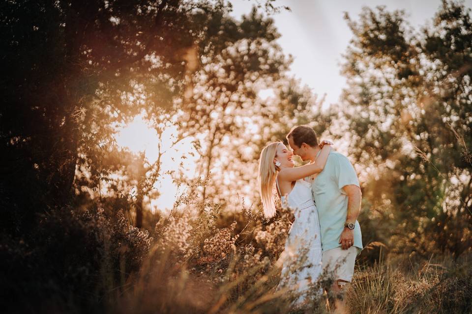 Novios abrazados al atardecer en medio del campo