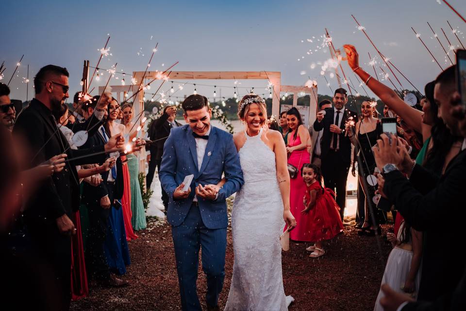 Pareja feliz caminando en medio de los invitados con bengalas