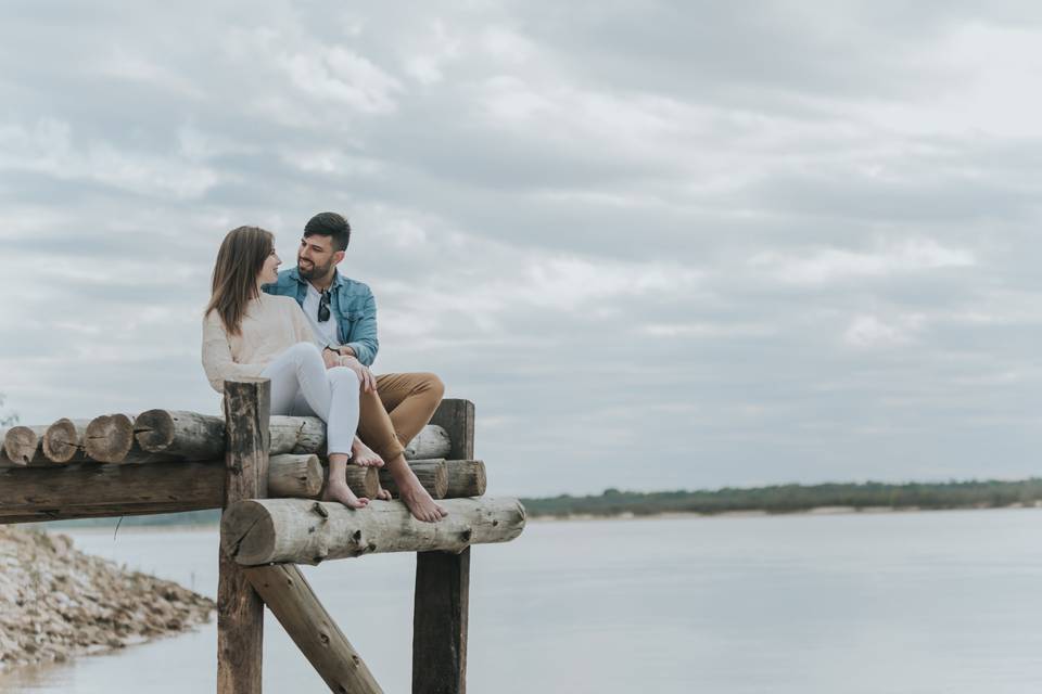 Novios sentados en un puente frente a un lago