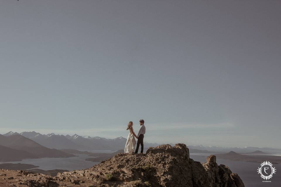 Novios en la cima de la montaña tomándose de las manos