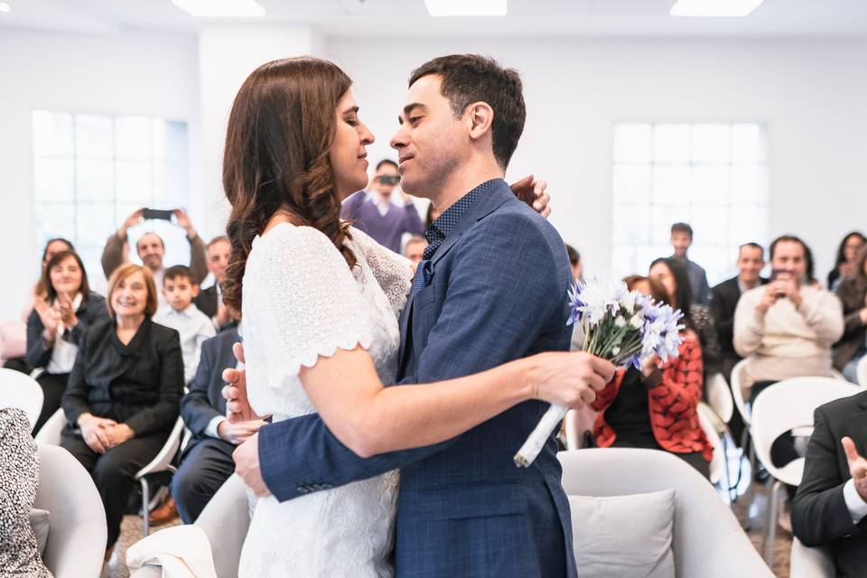 Novios abrazados frente a sus seres queridos