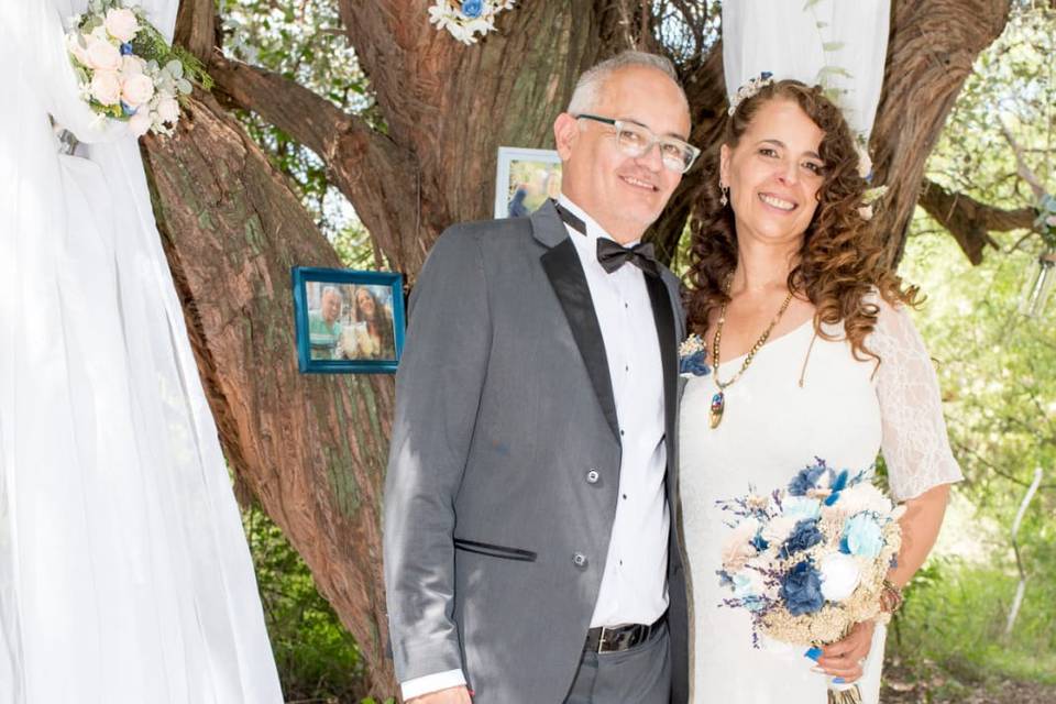 Pareja posando en un árbol decorado con flores y telas