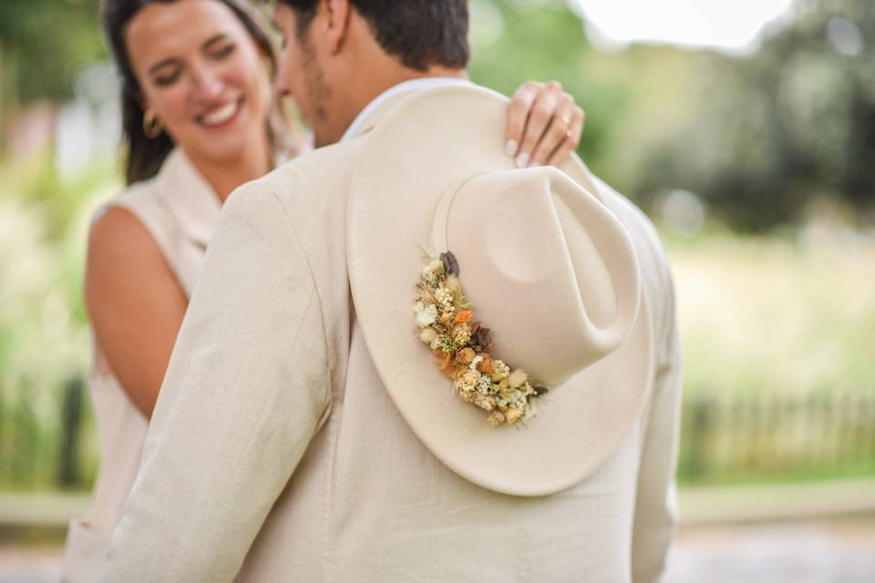 Novia con un sombrero beige tocando el hombro de su pareja